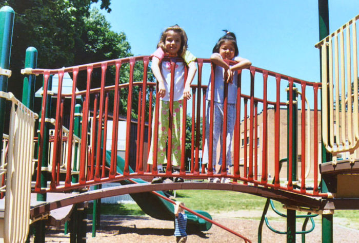 Two young children happy on playground bridge