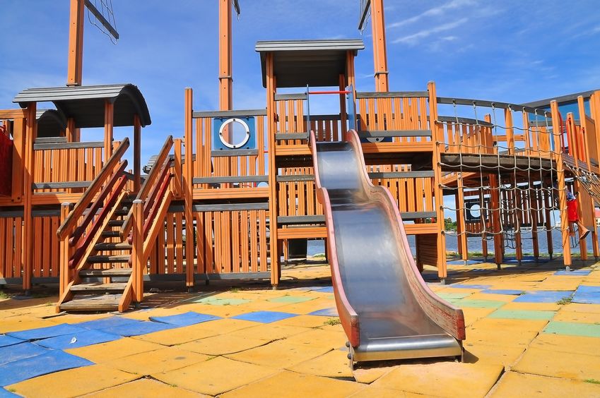 colorful playground for children's focus on slider, with worn rubber tile surfacing
